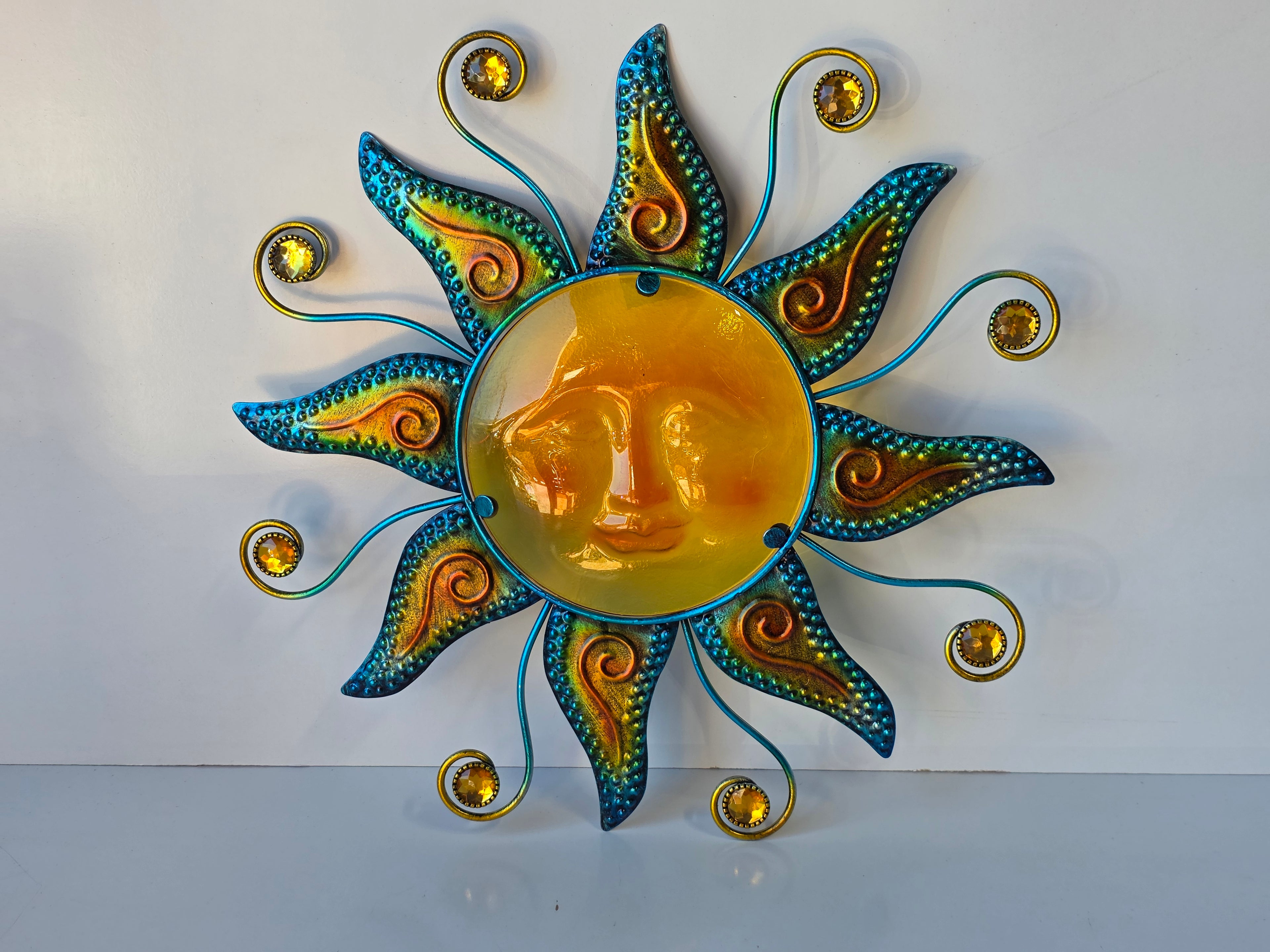 Colorful Metal and Glass Sun Wall Art with Amber Face and Blue-Green Rays Decor Piece